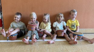 Kinder sitzen im Turnsaal